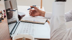 Ein junger Mann sitzt am Laptop und arbeitet allein, ein Gesicht ist nicht zu erkennen.