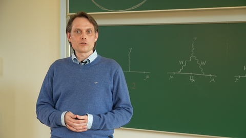 Professor Dominik Stöckinger vor einer mit Formeln beschriebenen, grünen Tafel.