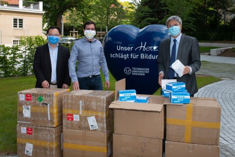 TUD-Rektor Prof. Hans Müller-Steinhagen (r.) nimmt 20.000 Mund-Nasen-Schutzmasken von Prof. Dr. Xinliang Feng (l.) und Dr. Martin Lohe (Sixonia Tech GmbH) in Empfang.