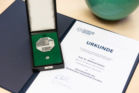 Die Ehrenmedaille ist links im Bild zu sehen, sie liegt im Etui auf der Verleihungsurkunde für Prof. Hacker