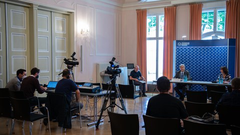 Pressekonferenz zur Verabschiedung von Prof. Müller-Steinhagen. Er sitzt im Podium, im Vordergrund Journalisten mit Ausrüstung.