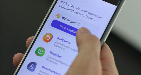 Ein von der rechten Hand schräg gehaltenes Smartphone, eine Liste von Apps ist übereinander zu sehen.