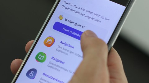 Ein von der rechten Hand schräg gehaltenes Smartphone, eine Liste von Apps ist übereinander zu sehen.