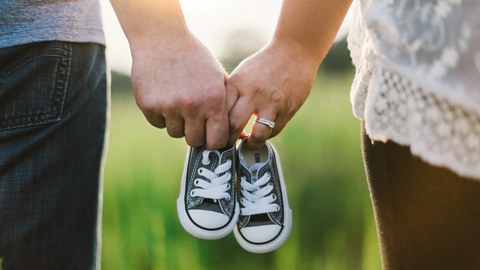 Ein Paar hält Babyschuhe