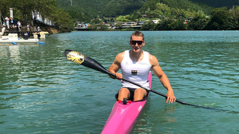 Mann sitzt in Einer-Kajak auf dem Wasser.