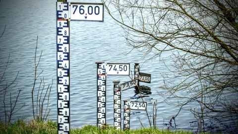 Wasserstandsmesser stehen auf einer Wiese vor einem Gewässer