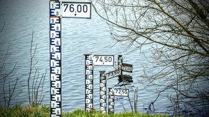 Wasserstandsmesser stehen auf einer Wiese vor einem Gewässer