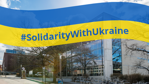 Foto des Hörsaalzentrums der TU Dresden, über das die Ukrainische Flagge geblendet ist, in der der Hashtag "Solidarity with Ukraine" steht. 