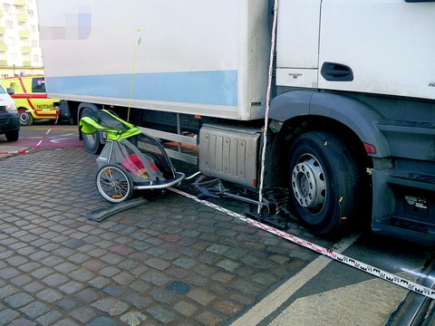 The image shows a truck that has turned into a children's bicycle trailer. Emergency vehicles can be seen in the background.
