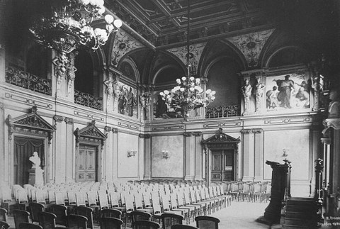 Schwarz-Weiß-Foto des bestuhlten Saals samt Rednerpult.