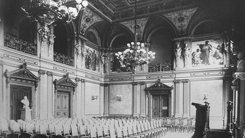 Schwarz-Weiß-Foto des bestuhlten Saals samt Rednerpult.