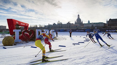 Ski-Langläufer beim Rennen auf Schnee vor der Kulisse der Dresdner Altstadt.