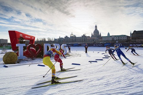 Ski-Langläufer beim Rennen auf Schnee vor der Kulisse der Dresdner Altstadt.