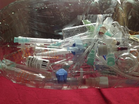 Abfall von gebrauchten Spritzen und kleine Behältnisse liegen in durchsichtigem Plastikbehälter.