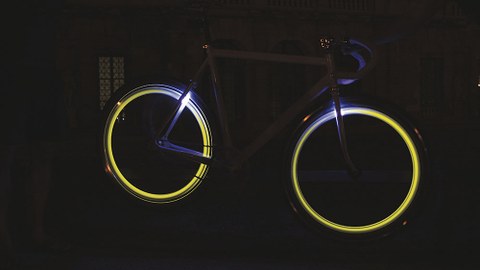 Fahrrad steht mit nachleuchtenden Reifen in der Dunkelheit.