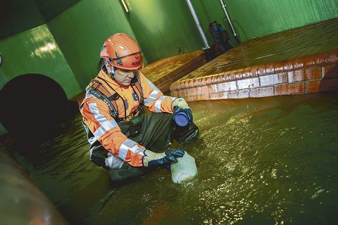 Ein Mitarbeiter der Stadtentwässerung Dresden entnimmt dem Abwasser eine Probe.