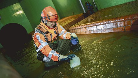 Ein Mitarbeiter der Stadtentwässerung Dresden entnimmt dem Abwasser eine Probe.