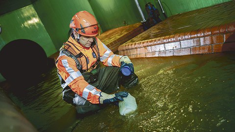 Ein Mitarbeiter der Stadtentwässerung Dresden entnimmt dem Abwasser eine Probe.