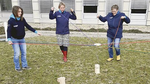 Drei Kolleginnen des DHSZ stehen auf einer Wiese. Sie probieren das Teamspiel »Tower of power« aus.