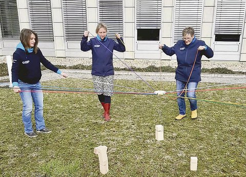 Drei Kolleginnen des DHSZ stehen auf einer Wiese. Sie probieren das Teamspiel »Tower of power« aus.