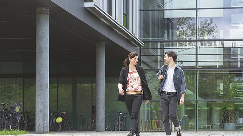 Ramona Nitzsche und Toni Blümel unterhalten sich im Gehen vor einem Gebäude.