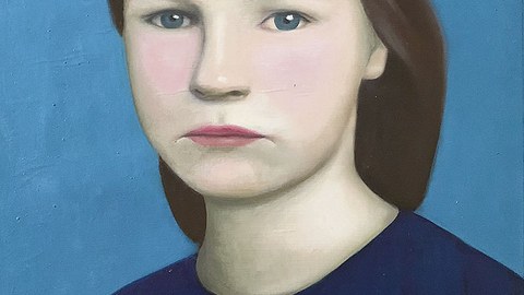 Porträt eines Mädchens, das vor einem blaue Hintergrund sitzt oder steht.