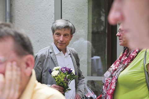 Dr. Lienert, im Gespräch mit einem nicht zu sehenden Gast, hält einen kleinen Blumenstrauß in der Hand.