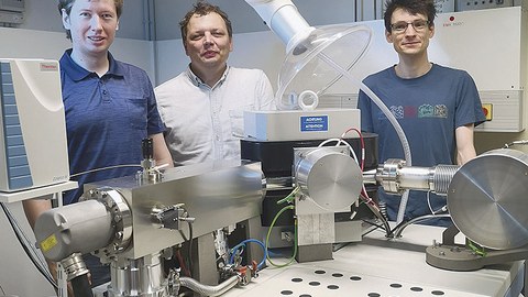 Stephan Beil, Björn Günther und Patrick Wordell-Dietrich stehen an einem Isotopen-Massenspektrometer mit Blick zum Betrachter.