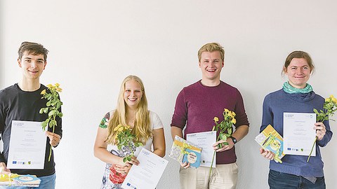 Die Gewinner stehen nebeneinander, halten ihre Urkunde und Blumen in der Hand.