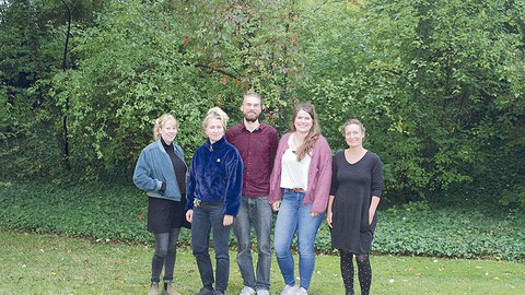 Das ELF-Team steht vor einem grünen Busch auf der Wiese.