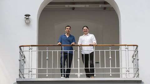 Die Schaufler-Lab-Künstler Christian Kosmas Mayer und Anton Ginzburg stehen an einer Balkonbrüstung in der Altana-Galerie. Sie schauen nach unten.
