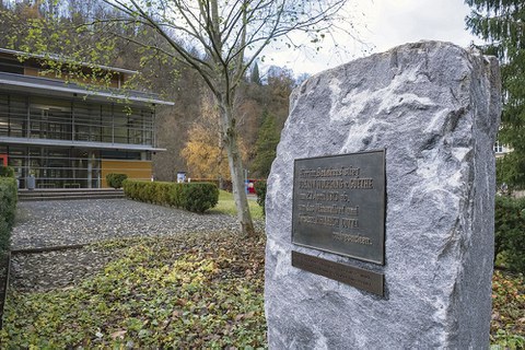 Auf einem Steinbloch ist eine dunkle Metalltafel angebracht.