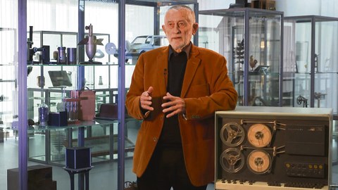 Karl Clauss Dietel in der Dauerausstellung der Kustodie 2018; er stützt sich mit dem linken Arm auf das in der Ausstellung gezeigte Exemplar des D4a.