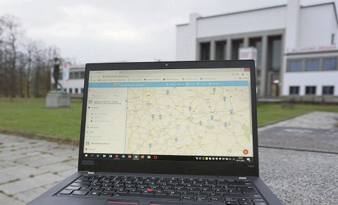 Ein geöffneter Laptop steht auf einem Weg vor dem Hygiene-Museum Dresden. Auf dem Bildschirm ist die Lernlandkarte Sachsen geöffnet.
