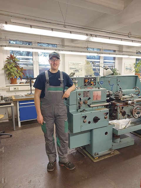 Nick Neubert steht neben einer Maschine in der Werkstatt.