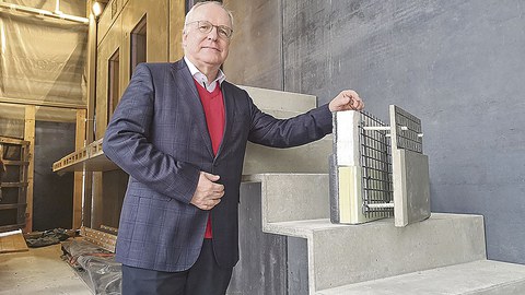 Prof. Curbach steht neben einem Abschnitt von einer Treppe und hält ein Demonstrationsstück fest.