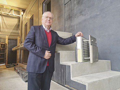 Prof. Curbach steht neben einem Abschnitt von einer Treppe und hält ein Demonstrationsstück fest.