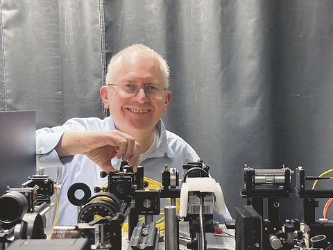 Prof. Czarske steht hinter einem Versuchsaufbau für Laserstrahlen.