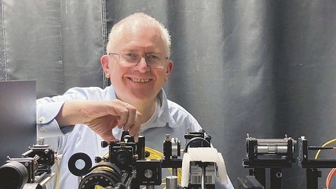Prof. Czarske steht hinter einem Versuchsaufbau für Laserstrahlen.
