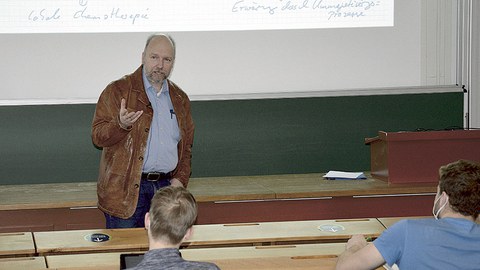 Prof. Odenbach steht im Hörsaal vor der Tafel. Er spricht zu Zuhörern. In den Bankreihen sitzen einige Studierende. 