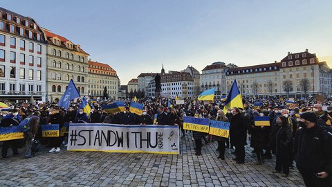 Auf dem Dresdner Neumarkt demonstrieren viele Menschen. Einige tragen ein Transparente und Ukrainische Flaggen.