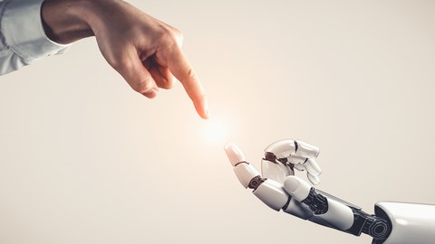 Menschliche Hand und Roboterhand berühren sich fast.