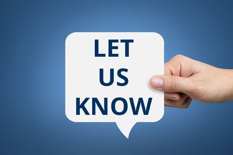 Foto: Hand hält eine weiße Sprechblase mit der Aufschrift "Let us know" auf blauem Hintergrund