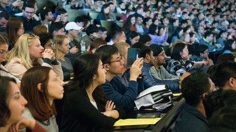 Internationale junge Leute sitzen in einem vollen Hörsaal