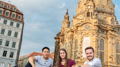 drei junge Menschen sitzen auf dem Neumarkt vor der Frauenkirche