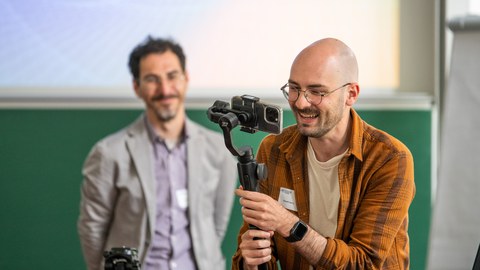 zwei Männer mit einer Handykamera in Workshopsituation