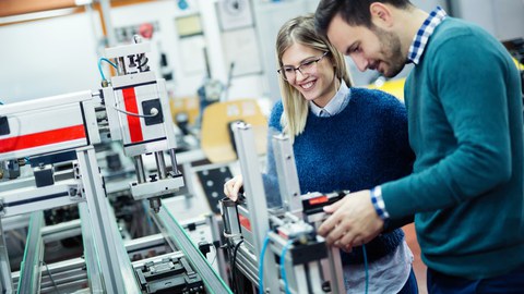 zwei Personen stehen an einer hochtechnisierten Anlage