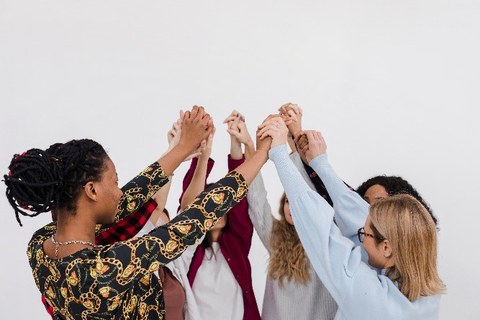 verschiedene Frauen stehen im Kreis - die Hände treffen sich in der Mitte