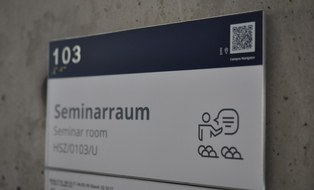 Das Foto zeigt ein Hinweisschild. Dieses sagt aus, dass es sich bei Raum 103 um einen Seminarraum handelt.