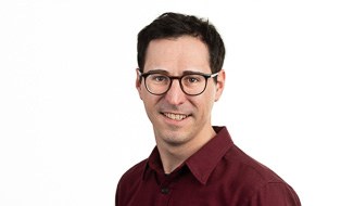 man with dark coloured hair and glasses